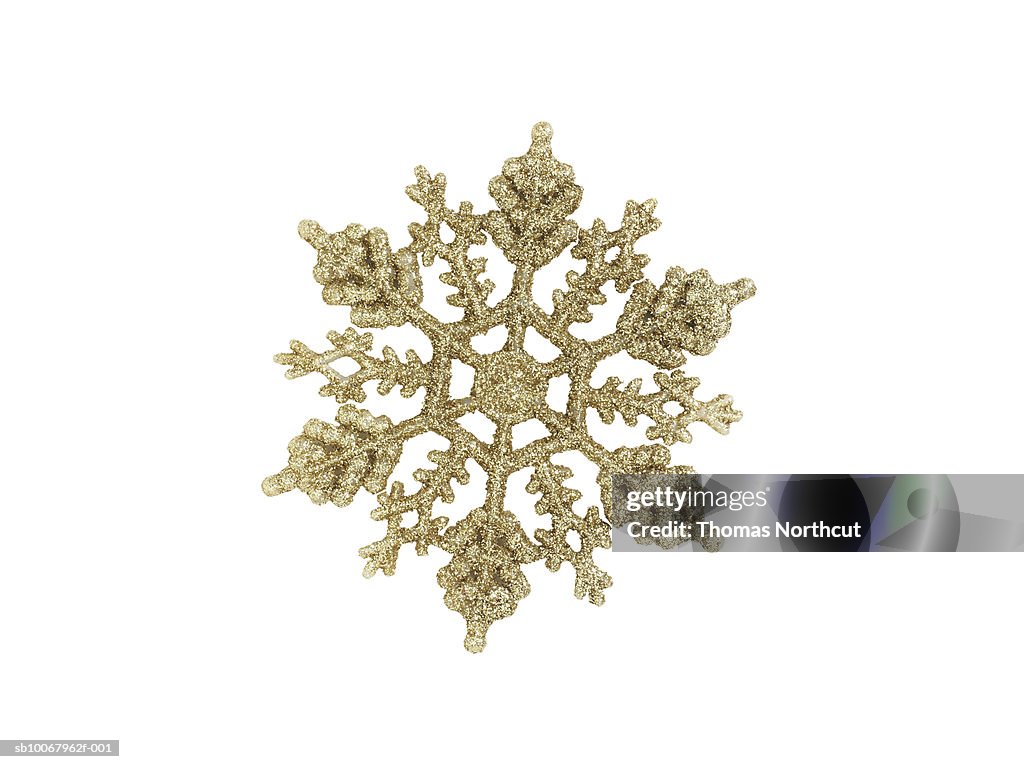 Gold snow flake ornament on white background