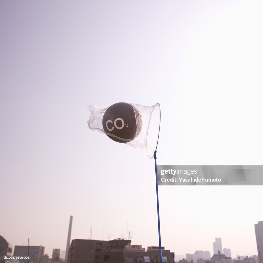 Net catching carbon dioxide molecule over city at dusk