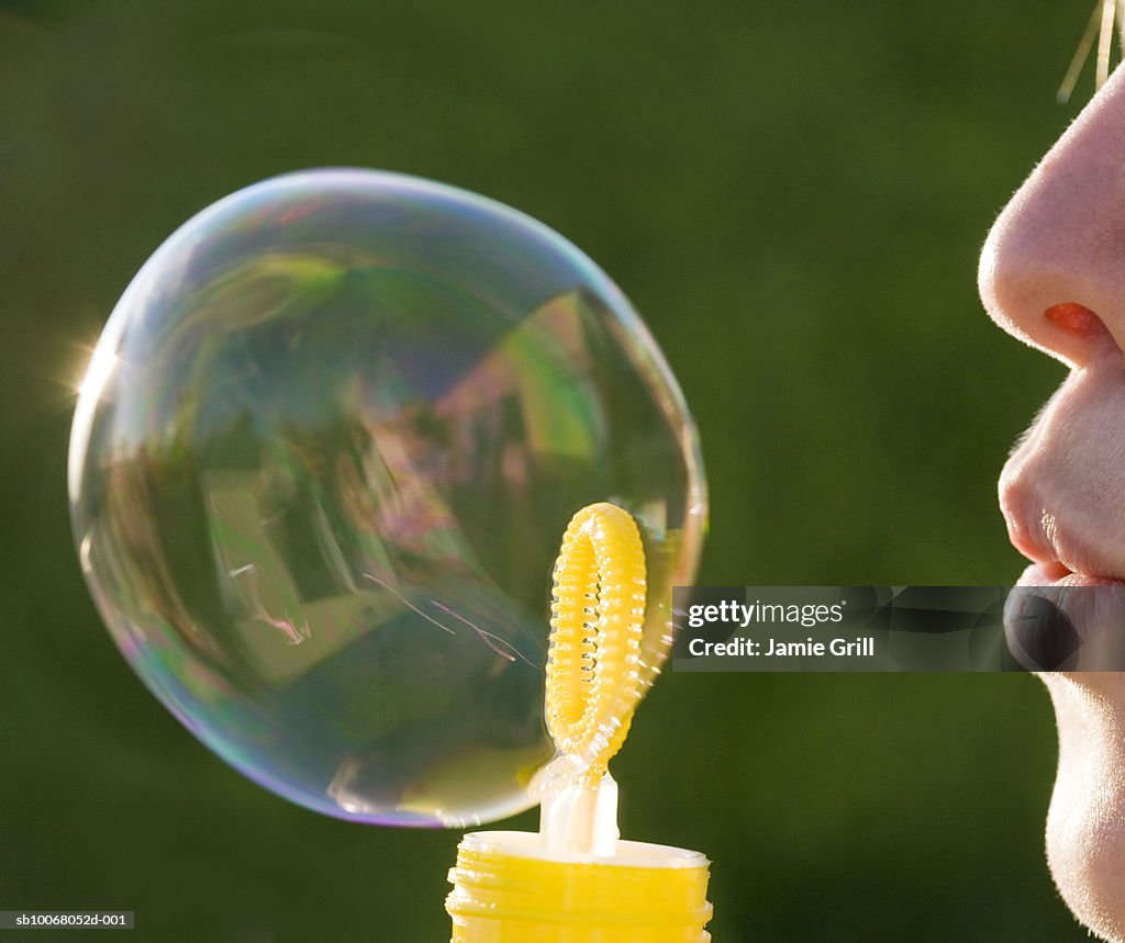 Young woman blowing bubble, close up, side view
