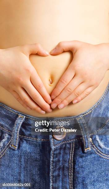 hands forming heart shape around navel, close-up, mid section - belly button stock pictures, royalty-free photos & images