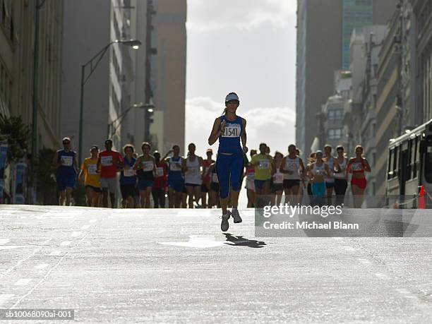 woman running in front of pack in marathon - marathon stockfoto's en -beelden