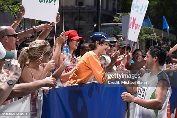 son shaking hands with father who ran marathon - marathon zuschauer stock-fotos und bilder