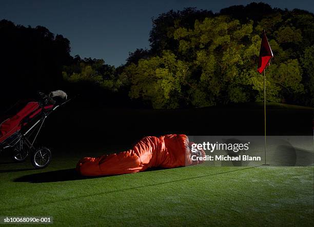 man sleeping on golf course in sleeping bag - saco de dormir fotografías e imágenes de stock