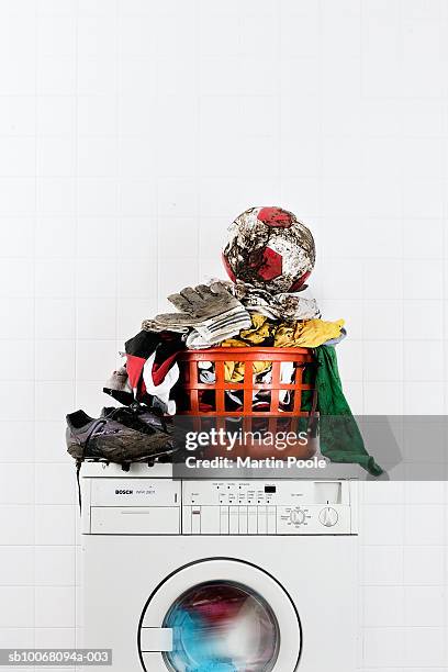 muddy football kit with ball and boots in laundry basket on washing machine - soccer uniform foto e immagini stock