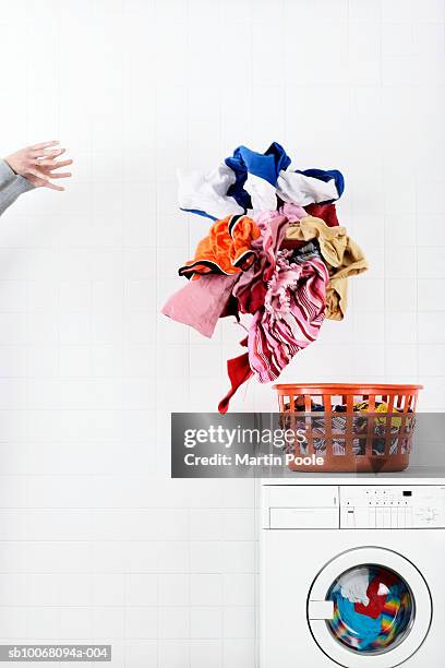 woman throwing pile of laundry to basket on washing machine - hand wasser stockfoto's en -beelden