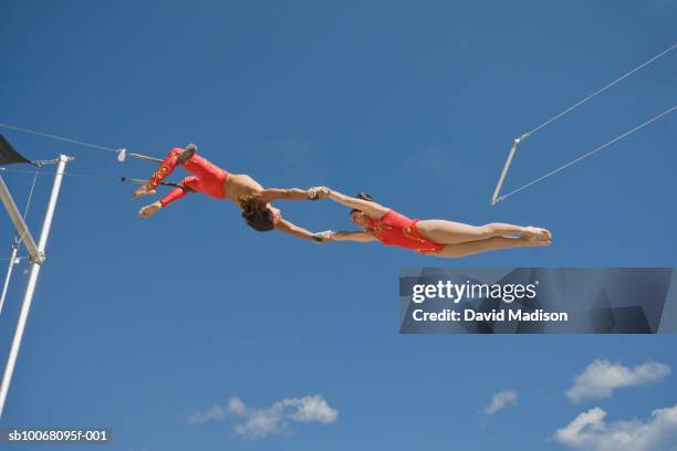 male trapeze artist catching woman, low angle view - zirkus stock-fotos und bilder