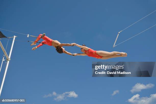 male trapeze artist catching woman, low angle view - trapéziste photos et images de collection