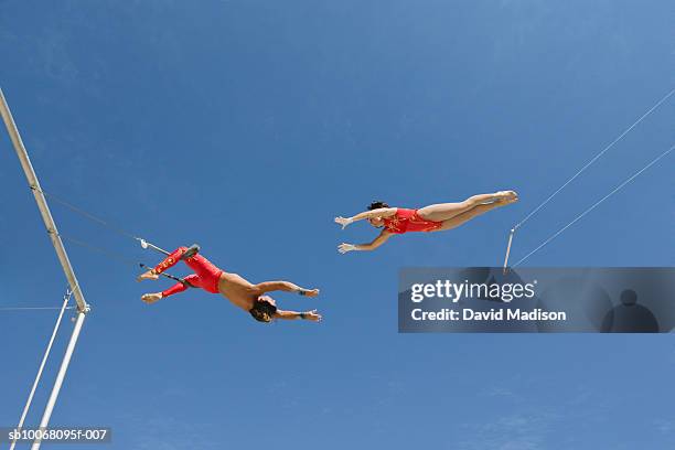 male trapeze artist catching woman, low angle view - trapeze artist stock pictures, royalty-free photos & images