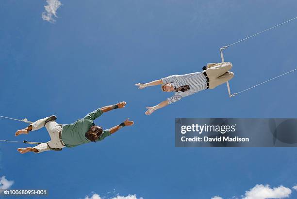 male trapeze artist catching man, low angle view - caught in the act stock-fotos und bilder