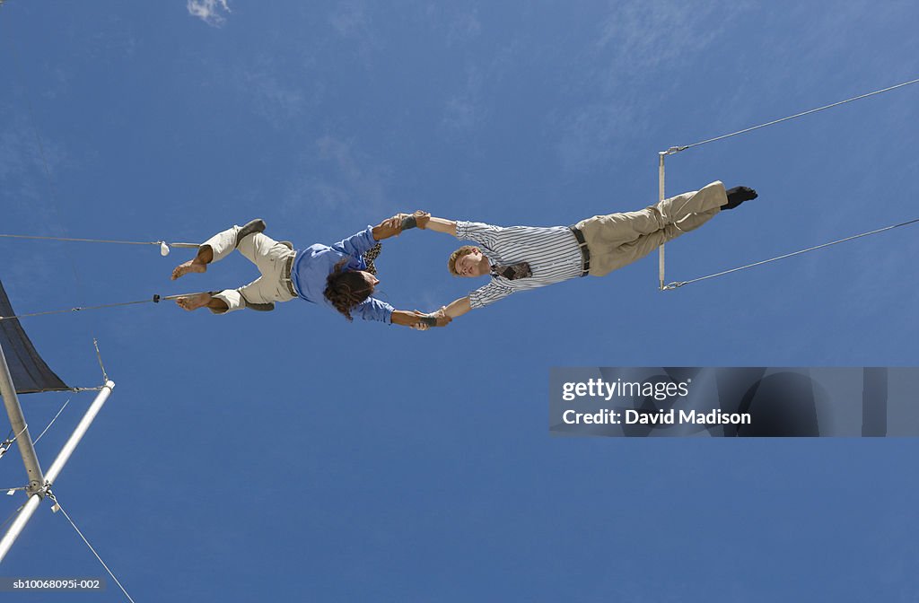 Male trapeze artist catching man, low angle view