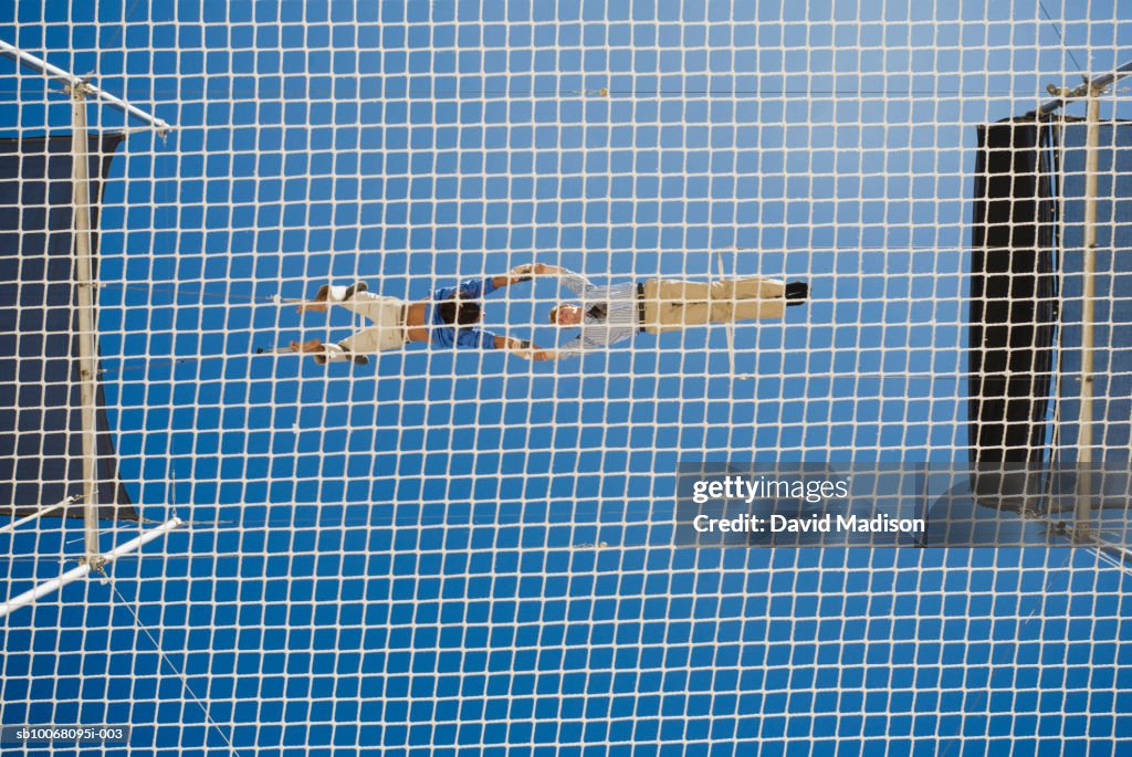 Male trapeze artist catching man, low angle view