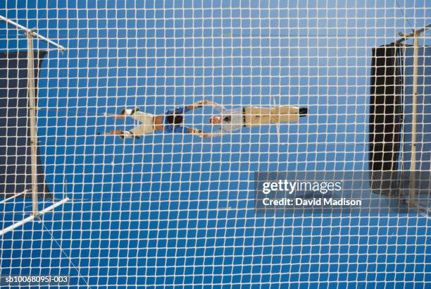 male trapeze artist catching man, low angle view - safety net stock pictures, royalty-free photos & images