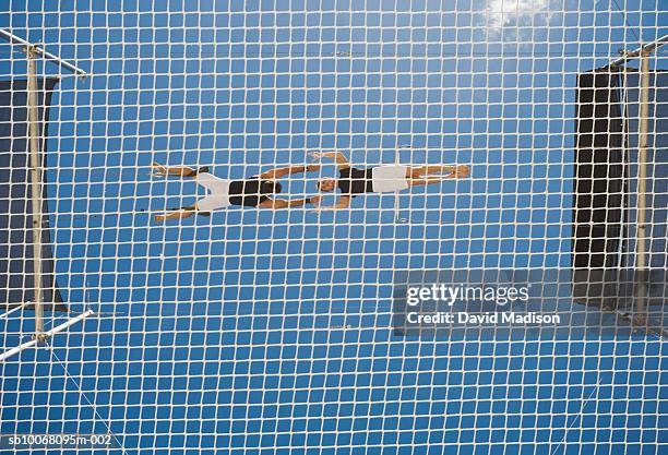 male trapeze artist catching man, low angle view - safety net stock pictures, royalty-free photos & images