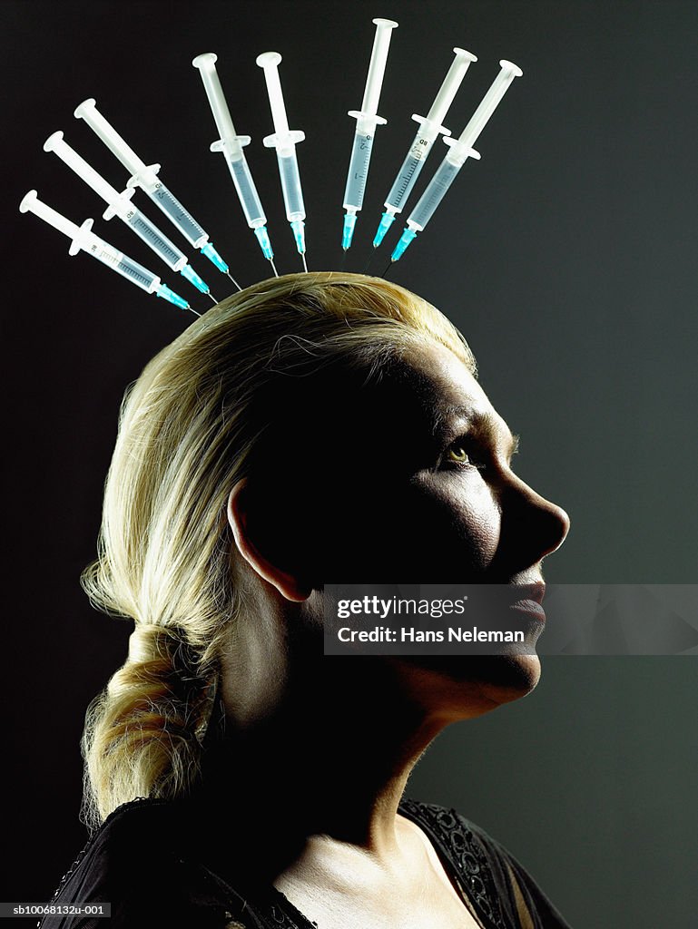 Woman with needles sticking in head, studio shot
