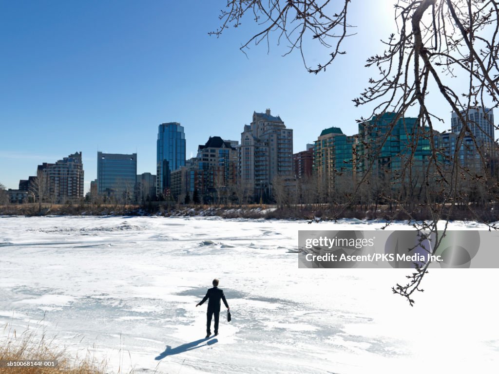 Businessman standing on frozen river, rear view