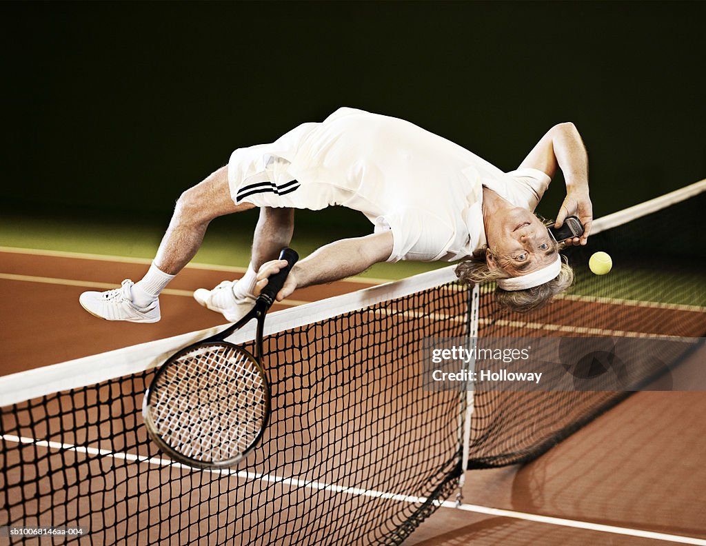 Mature man playing tennis and using mobile phone