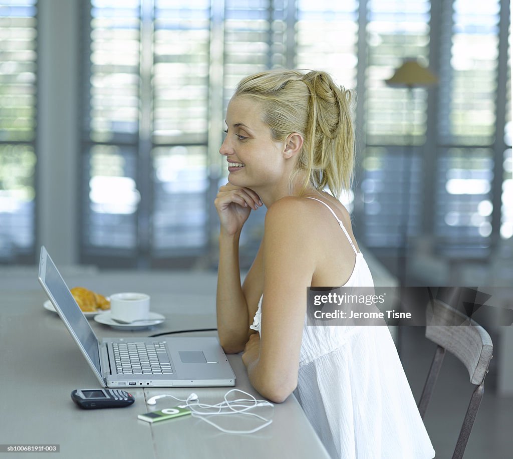 Young woman using laptop sitting at table indoors, elevated view