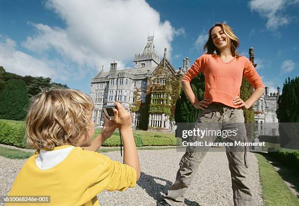 boy (8-9) photographing girl (12-13) in front of castle - irish family stock pictures, royalty-free photos & images