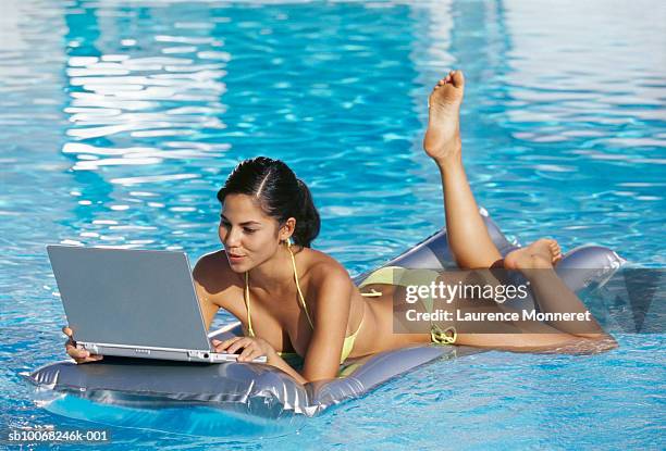 young woman floating on pool raft with laptop - pool raft imagens e fotografias de stock