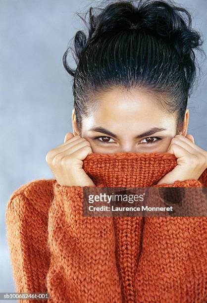 studio portrait of young woman covering face with turtleneck collar - polo necks stock pictures, royalty-free photos & images