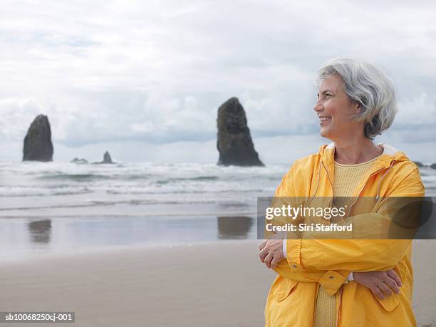 senior woman on beach with arms crossed, smiling - oregon stock pictures, royalty-free photos & images