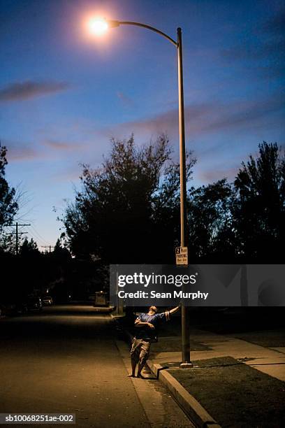 drunk man leaning on lamp post at night - street light post stock pictures, royalty-free photos & images