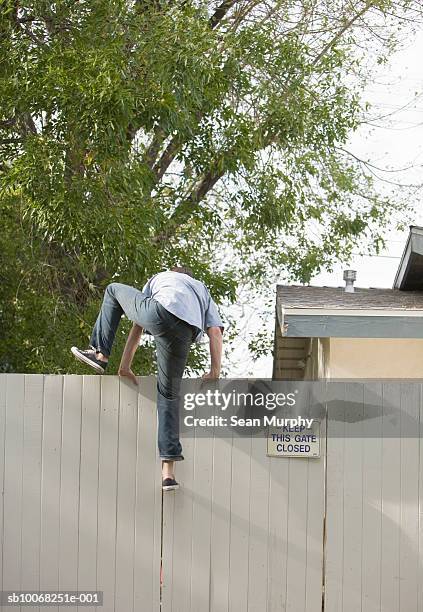 man jumping over fence, rear view - man climbing fence stock pictures, royalty-free photos & images