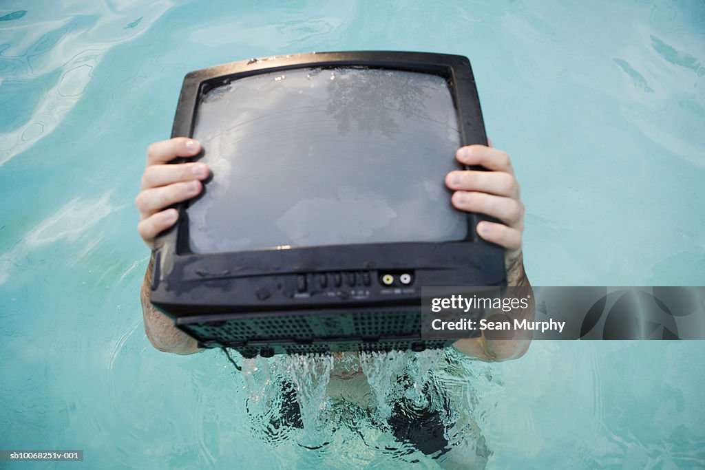 Man in swimming pool with television set