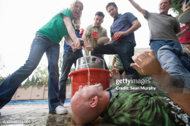 woman dispensing beer directly from keg into mouth of man lying on ground - man open mouth stock pictures, royalty-free photos & images