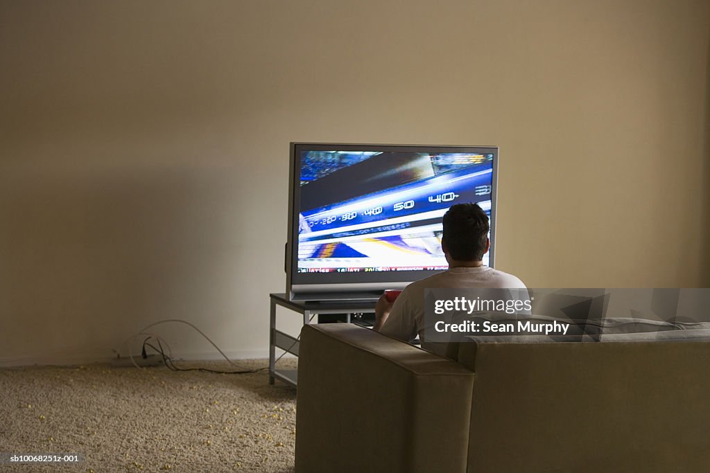 Junger Mann sitzt auf sofa Fernsehen, Rückansicht