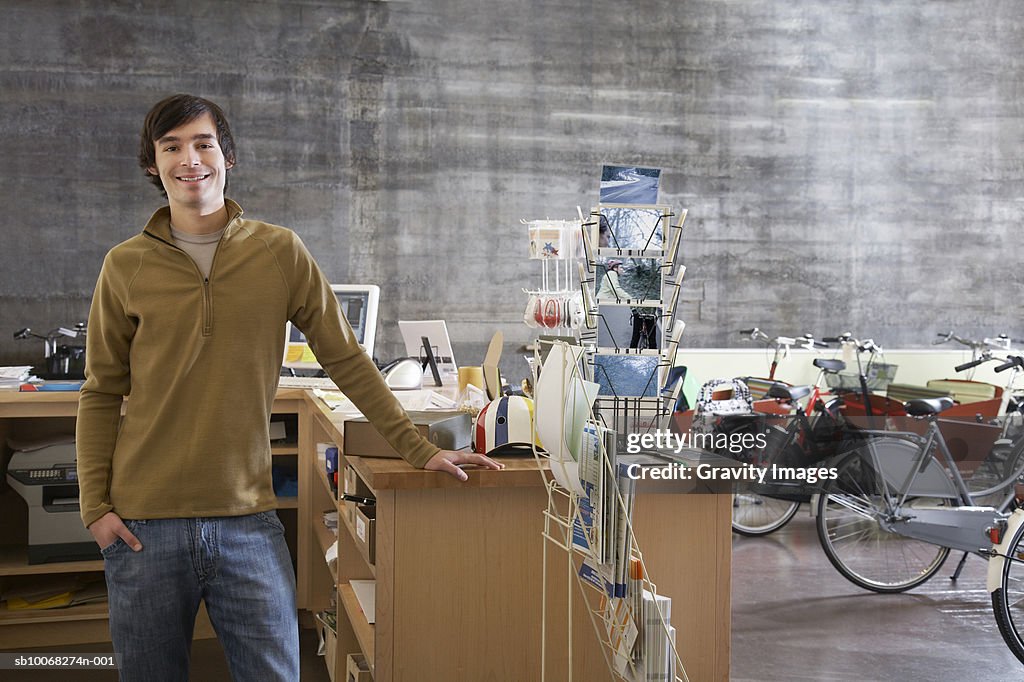 Bicycle shop owner standing at counter, smiling, portrait