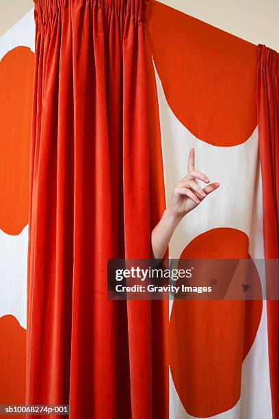 women's hand coming from behind changing room curtain - anprobekabine stock-fotos und bilder