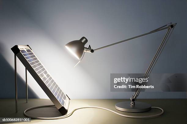solar panel connecting to illuminated desk lamp, close-up - schreibtischlampe stock-fotos und bilder