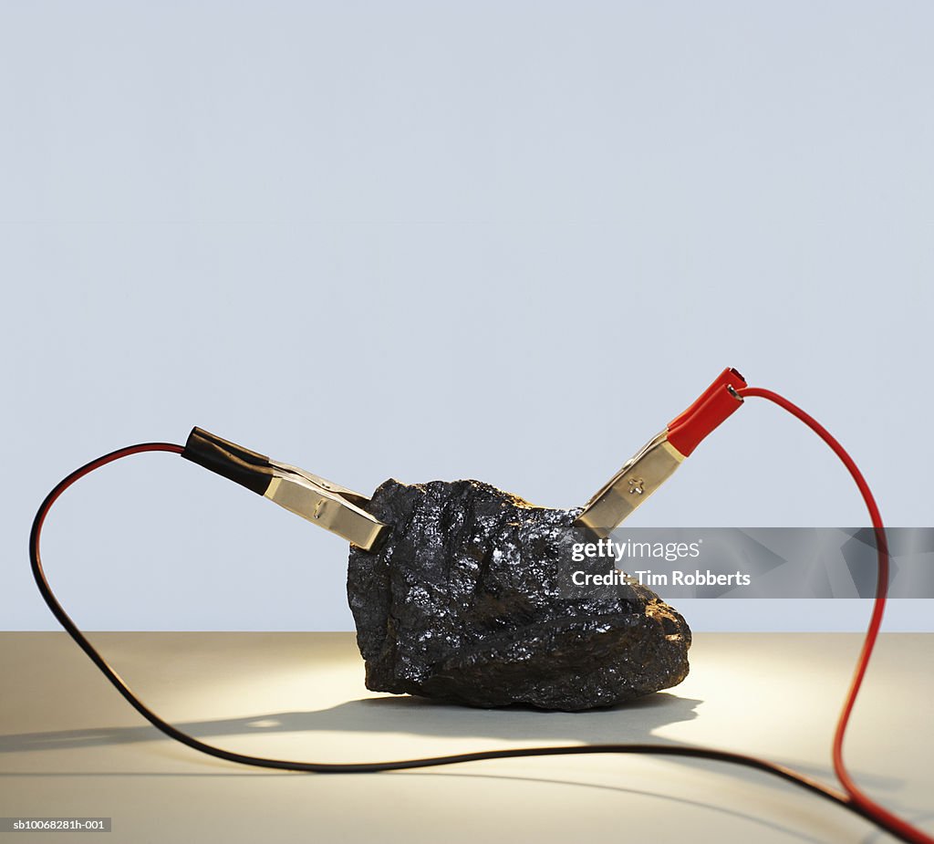 Lump of coal with red and black power cables attached, close-up