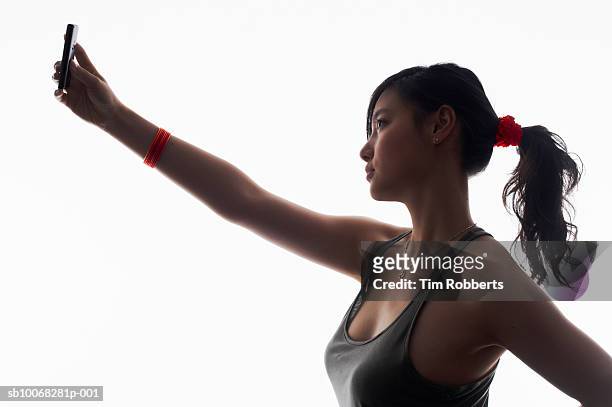 young woman photographing self with camera phone, side view, close-up - call to arms stock pictures, royalty-free photos & images