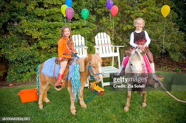 girls (4-7) sitting on pony in back yard, smiling - pony stock pictures, royalty-free photos & images