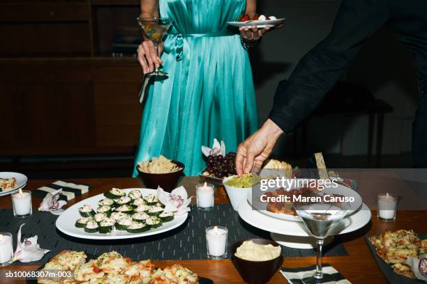 man and woman eating appetizers at cocktail party - cocktail dress stock-fotos und bilder