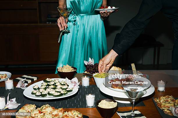 man and woman eating appetizers at cocktail party - cocktail party dress stock pictures, royalty-free photos & images