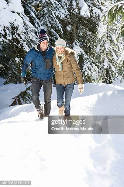 couple walking in snow near forest - mid adult couple stockfoto's en -beelden
