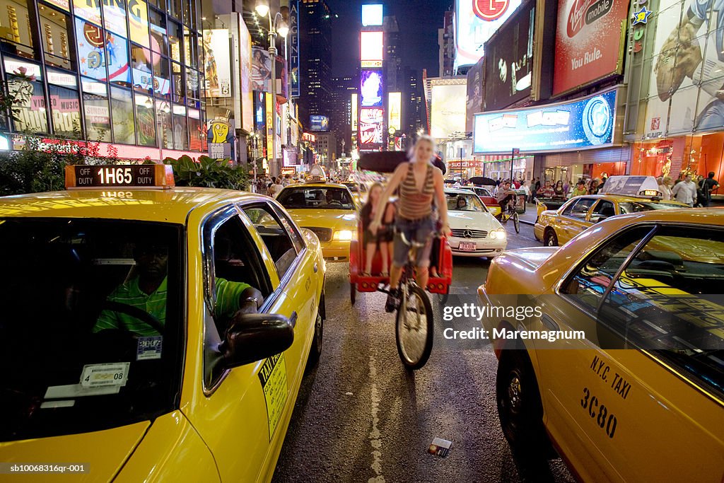 USA, New York State, New York City, Manhattan, rickshaw driver riding between yellow cabs in street