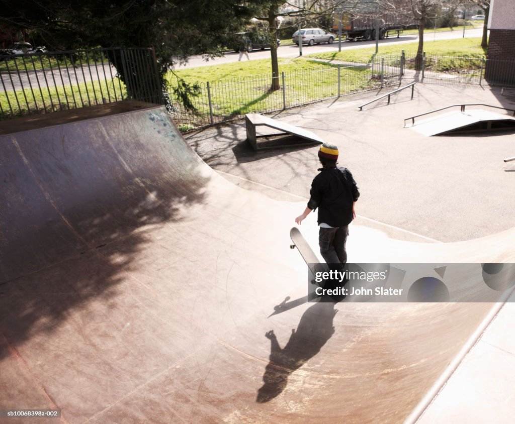 Boy (10-11) practicing skateboarding on ramp, rear view