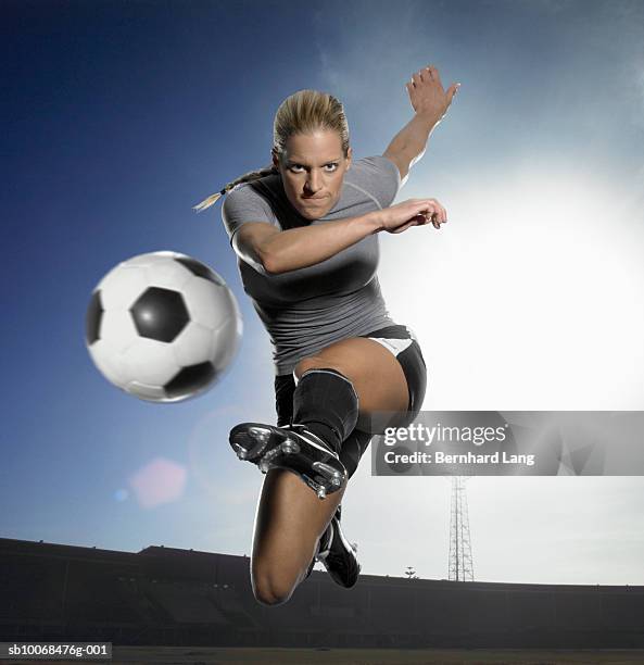 young woman kicking football in stadium (digital composite) - kicking soccer stock pictures, royalty-free photos & images