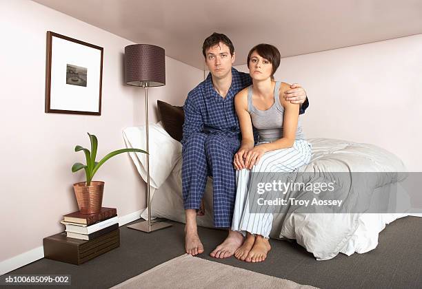 couple sitting on bed in miniature bedroom, portrait - junge frau bett sitzen blick in die kamera stock-fotos und bilder