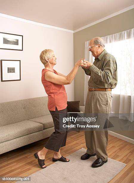 senior couple dancing in living room, holding hands, side view - old carpet stock pictures, royalty-free photos & images
