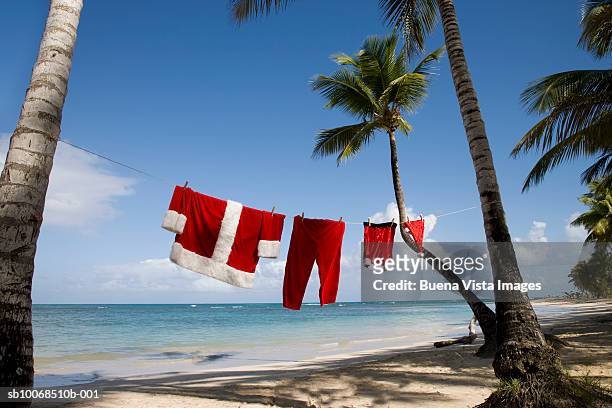 santa claus costume hanging on clothesline on tropical beach - caribbean christmas 個照片及圖片檔