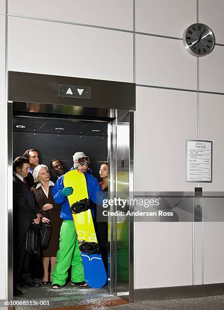 young man with snow board with business people in elevator - skikleidung stock-fotos und bilder