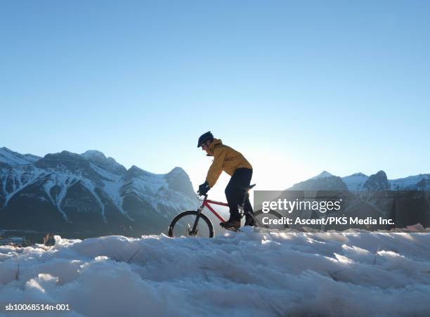 mountain biker riding on trail through snow - canmore alberta stock pictures, royalty-free photos & images