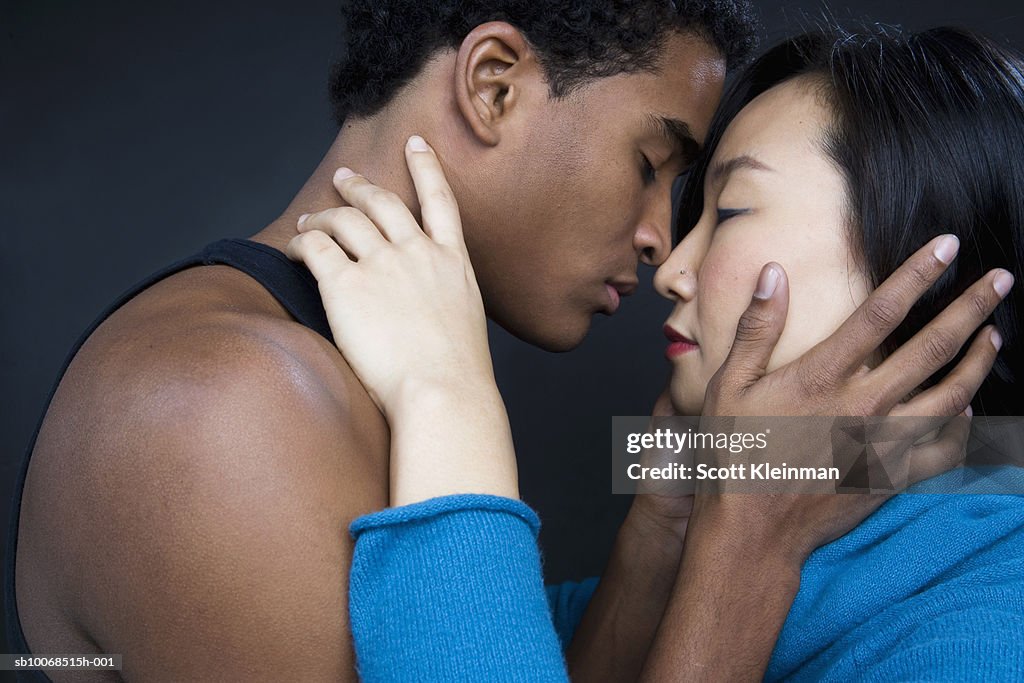 Studio shot of young couple about to kiss, side view