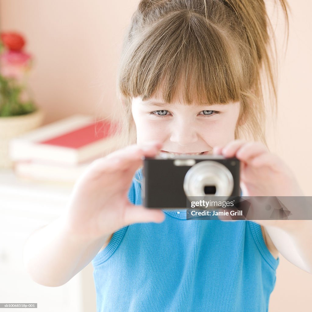 Girl (6-7) photographing with digital camera, smiling