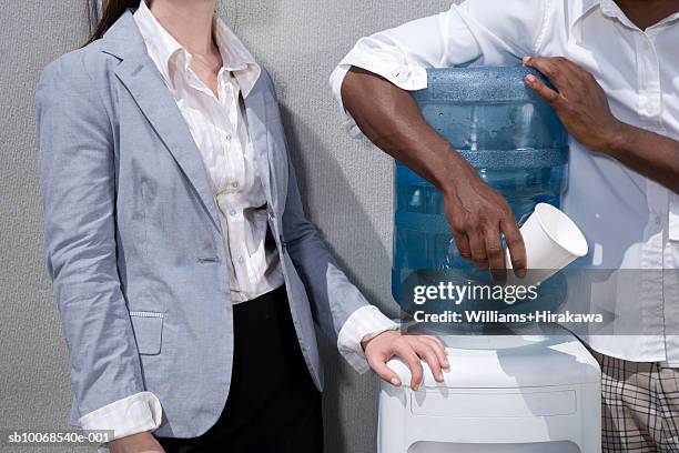 two office workers standing by water cooler, mid section - water cooler stock pictures, royalty-free photos & images